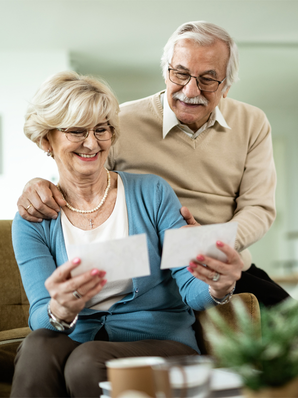 Happy senior couple feeling nostalgic while looking at their photo album at home.